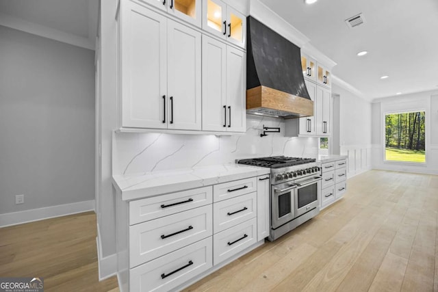 407 Thunder Rd, Buford, GA 30518 - kitchen with double oven range, custom range hood, light wood-type flooring, white cabinets, and wainscoting