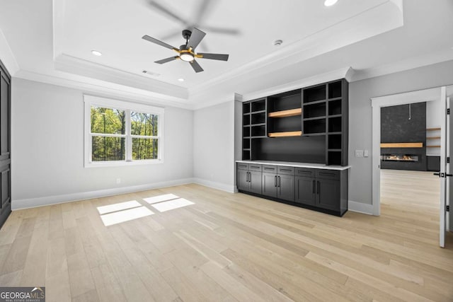 407 Thunder Rd, Buford, GA 30518 - unfurnished living room featuring a tray ceiling, a glass covered fireplace, a ceiling fan, light wood-style flooring, and ornamental molding