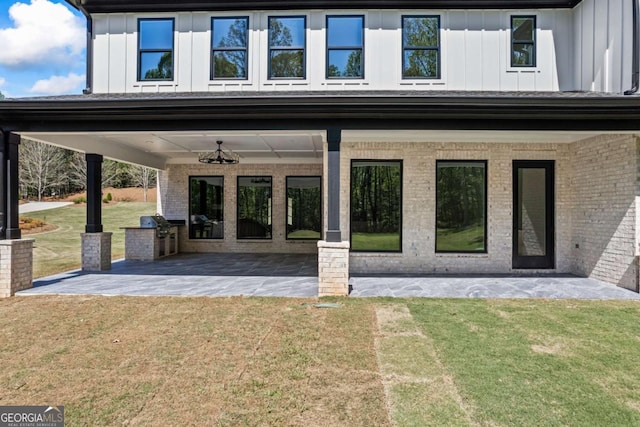 407 Thunder Rd, Buford, GA 30518 - property entrance featuring board and batten siding, brick siding, a patio, and a yard