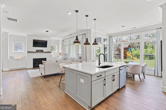 229 Widener Way, Peachtree City, GA 30269 - kitchen with light wood-style floors, a center island with sink, hanging light fixtures, light countertops, and crown molding