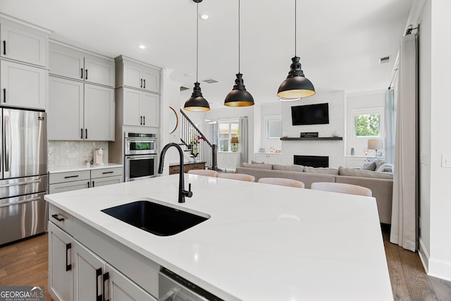 229 Widener Way, Peachtree City, GA 30269 - kitchen with stainless steel appliances, wood finished floors, a fireplace, decorative light fixtures, and recessed lighting