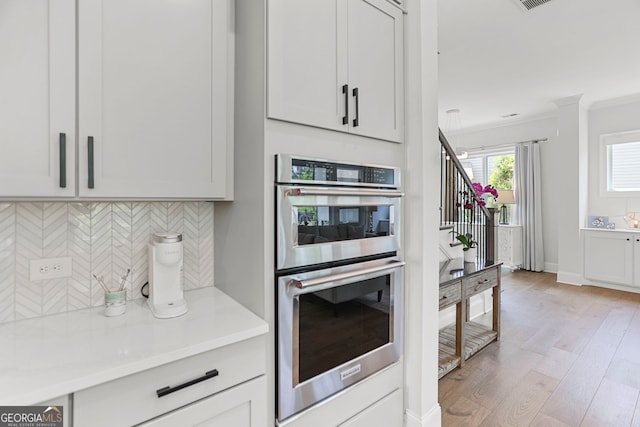 229 Widener Way, Peachtree City, GA 30269 - kitchen featuring double oven, backsplash, crown molding, light wood-type flooring, and light countertops