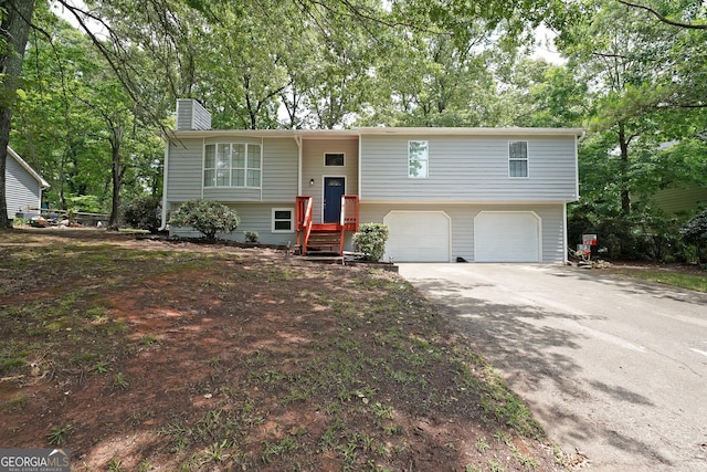 4191 Alaina Cir, Austell, GA 30106 - split foyer home with a garage, a chimney, driveway, and view of wooded area