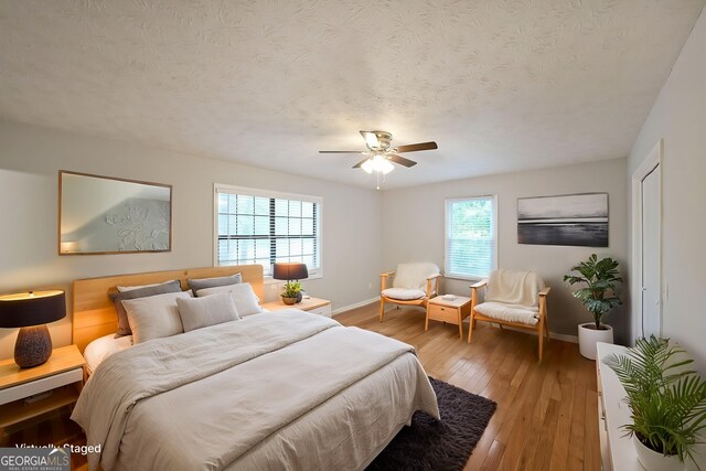 4191 Alaina Cir, Austell, GA 30106 - bedroom featuring baseboards, light wood-type flooring, a textured ceiling, and ceiling fan