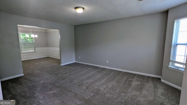 3881 Micah Ln, Ellenwood, GA 30294 - spare room featuring a textured ceiling, a chandelier, dark carpet, and plenty of natural light
