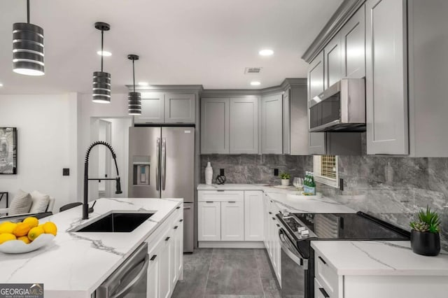 681 Fielding Ln SW, Atlanta, GA 30311 - kitchen with stainless steel appliances, gray cabinetry, light stone countertops, backsplash, and pendant lighting