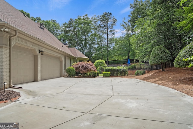10630 N Edgewater Pl, Johns Creek, GA 30097 - view of side of property with concrete driveway, an attached garage, a shingled roof, and brick siding