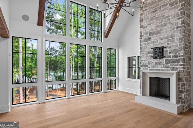 1111 Longview Commons, Greensboro, GA 30642 - unfurnished living room featuring high vaulted ceiling, a stone fireplace, wood finished floors, baseboards, and healthy amount of natural light