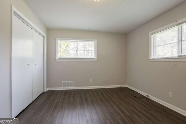 2311 Cherry Blossom Dr SW, Atlanta, GA 30331 - unfurnished bedroom featuring multiple windows, dark wood-type flooring, baseboards, and a closet
