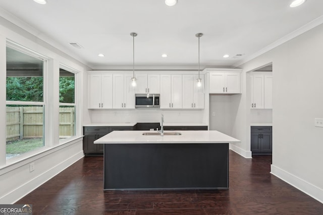 1158 Welch St SW, Atlanta, GA 30310 - kitchen featuring stainless steel microwave, an island with sink, hanging light fixtures, crown molding, and white cabinets