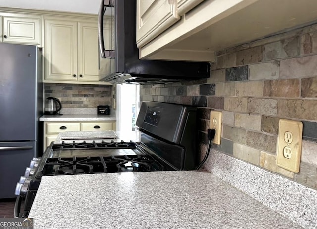 2674 Misty Rock Cv, Dacula, GA 30019 - kitchen with freestanding refrigerator, cream cabinets, light countertops, tasteful backsplash, and black microwave