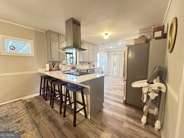 1815 Oak Spring St, Statham, GA 30666 - kitchen with island range hood, a peninsula, a breakfast bar, dark wood finished floors, and a textured ceiling