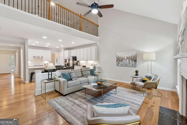 550 Mae Ln, Alpharetta, GA 30004 - living room featuring a ceiling fan, a high ceiling, a fireplace with flush hearth, light wood-type flooring, and baseboards