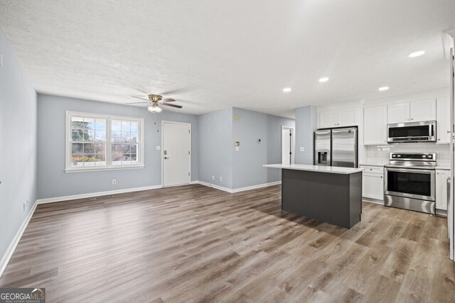 202 E 5th Ave, Winder, GA 30680 - kitchen featuring stainless steel appliances, a center island, white cabinets, a ceiling fan, and backsplash