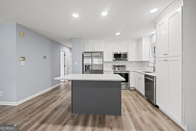 202 E 5th Ave, Winder, GA 30680 - kitchen with stainless steel appliances, a sink, a kitchen island, white cabinets, and tasteful backsplash