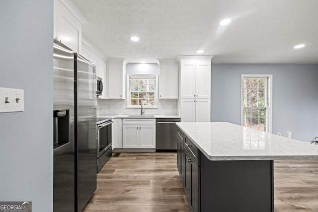 202 E 5th Ave, Winder, GA 30680 - kitchen featuring a sink, stainless steel appliances, white cabinets, a center island, and backsplash
