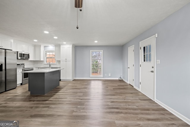 202 E 5th Ave, Winder, GA 30680 - kitchen with appliances with stainless steel finishes, white cabinetry, recessed lighting, a kitchen island, and plenty of natural light
