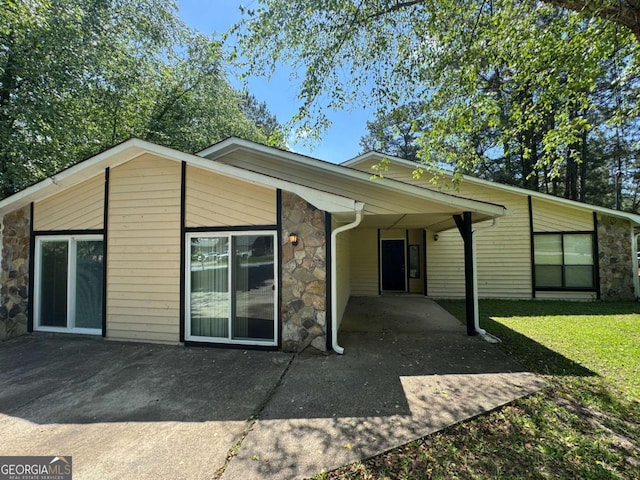 120 Squirrel Way, Atlanta, GA 30349 - rear view of house with stone siding, a patio, and a yard