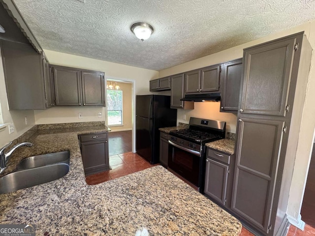 120 Squirrel Way, Atlanta, GA 30349 - kitchen featuring stainless steel range with gas stovetop, under cabinet range hood, freestanding refrigerator, dark stone counters, and a textured ceiling