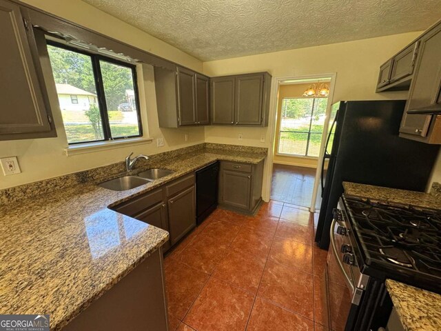 120 Squirrel Way, Atlanta, GA 30349 - kitchen featuring dishwasher, stainless steel gas range oven, dark tile patterned floors, stone countertops, and a chandelier
