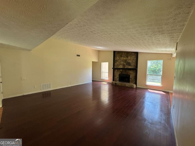 120 Squirrel Way, Atlanta, GA 30349 - unfurnished living room featuring dark wood-style floors, a textured ceiling, and a stone fireplace