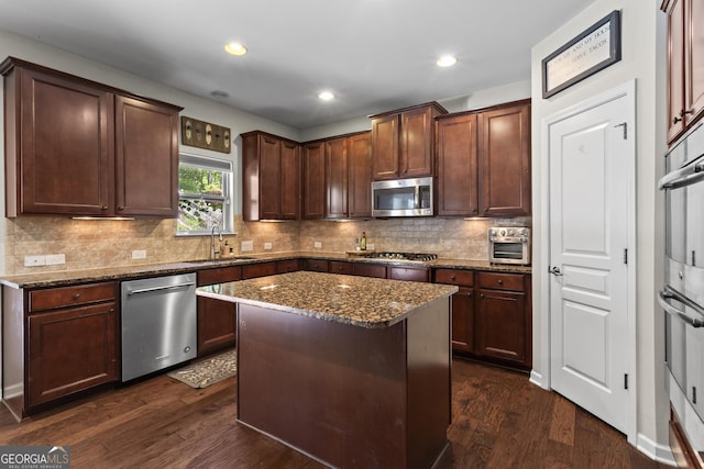 237 Parc Dr, Canton, GA 30114 - kitchen featuring stainless steel appliances, dark stone counters, dark wood-style flooring, backsplash, and a kitchen island