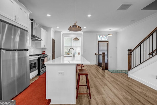 4565 Sims Park Overlook, Suwanee, GA 30024 - kitchen featuring stainless steel appliances, wall chimney range hood, a sink, crown molding, and light wood-style floors
