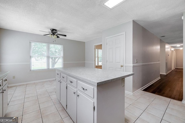 1282 Long Bridge Rd, Rincon, GA 31326 - kitchen featuring ceiling fan, light tile patterned floors, a kitchen island, white cabinets, and a textured ceiling