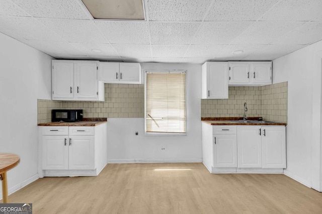 510 Edgewood Ave, Macon, GA 31201 - kitchen with dark countertops, black microwave, white cabinets, backsplash, and a drop ceiling