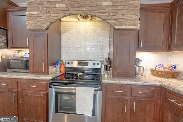 3251 Harrell Rd, Whigham, GA 39897 - kitchen featuring stainless steel appliances, tasteful backsplash, arched walkways, and brown cabinetry