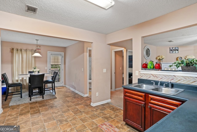 5865 El Segundo Way, Atlanta, GA 30349 - kitchen with a sink, dark countertops, a textured ceiling, dark brown cabinets, and pendant lighting