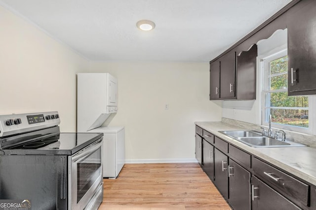 580 Vaughn Rd, Griffin, GA 30223 - kitchen with stacked washer / dryer, a sink, light wood finished floors, stainless steel electric stove, and baseboards