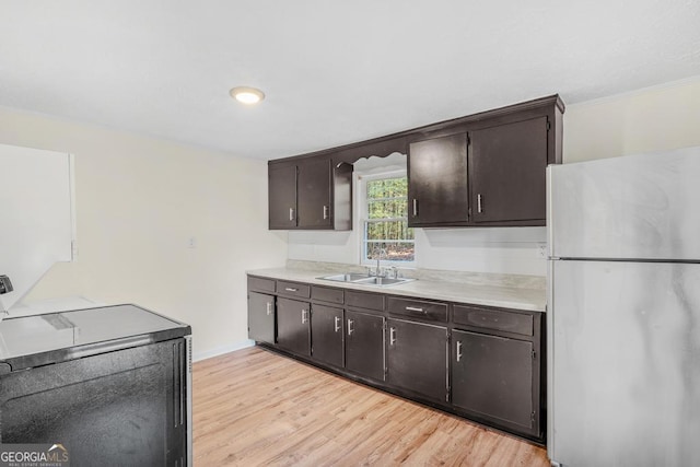 580 Vaughn Rd, Griffin, GA 30223 - kitchen with freestanding refrigerator, light countertops, dark brown cabinets, light wood-style flooring, and crown molding