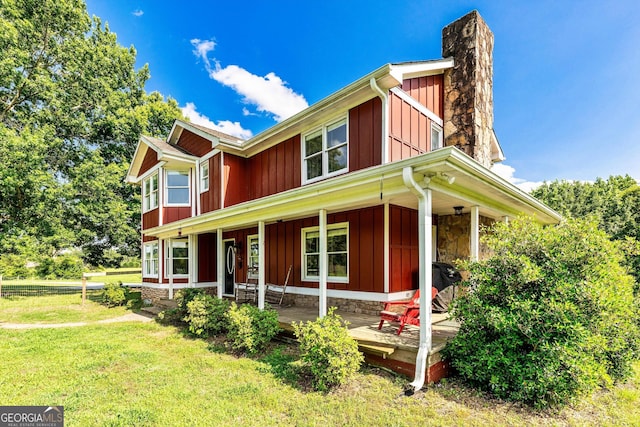 68 Riveree Rd, Brooks, GA 30205 - view of front facade with board and batten siding, a front lawn, a porch, and a chimney