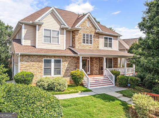2810 Promenade Pl, Buford, GA 30519 - view of front of house featuring stone siding, covered porch, a front yard, and a shingled roof