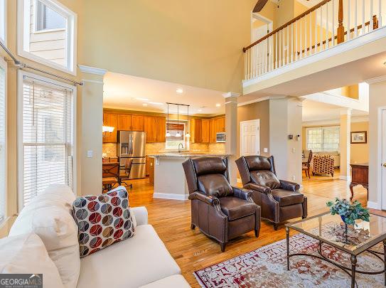 2810 Promenade Pl, Buford, GA 30519 - living area with light wood-style flooring, a towering ceiling, decorative columns, and recessed lighting