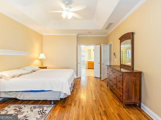 2810 Promenade Pl, Buford, GA 30519 - bedroom with a tray ceiling, wood finished floors, baseboards, crown molding, and ceiling fan