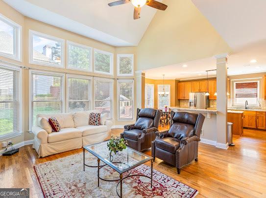 2810 Promenade Pl, Buford, GA 30519 - living room featuring light wood-type flooring, high vaulted ceiling, a ceiling fan, ornate columns, and recessed lighting