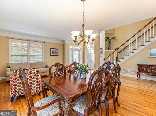 2810 Promenade Pl, Buford, GA 30519 - dining room with a chandelier, light wood-type flooring, stairs, baseboards, and ornamental molding