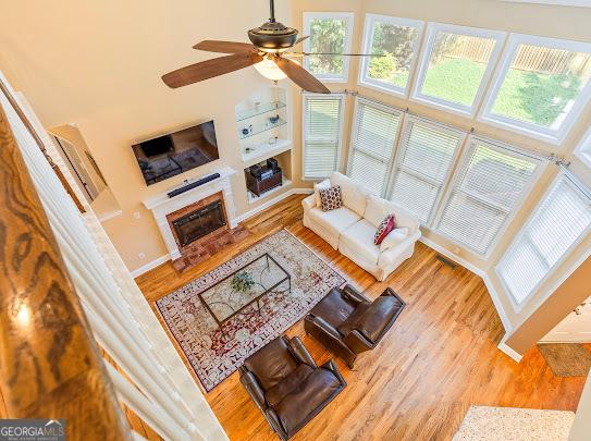 2810 Promenade Pl, Buford, GA 30519 - living room featuring a ceiling fan, wood finished floors, a glass covered fireplace, and baseboards