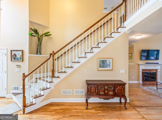 2810 Promenade Pl, Buford, GA 30519 - stairs with wood finished floors, a high ceiling, baseboards, and a glass covered fireplace