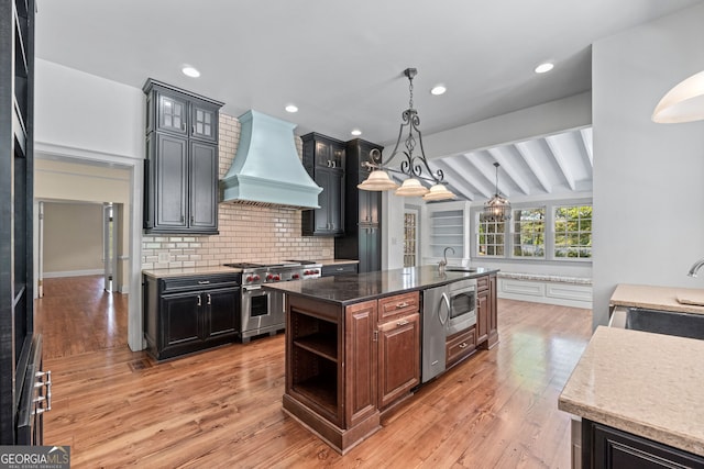 441 Crumbley Rd, Mcdonough, GA 30252 - kitchen featuring custom exhaust hood, appliances with stainless steel finishes, a kitchen island with sink, beam ceiling, and light wood-type flooring