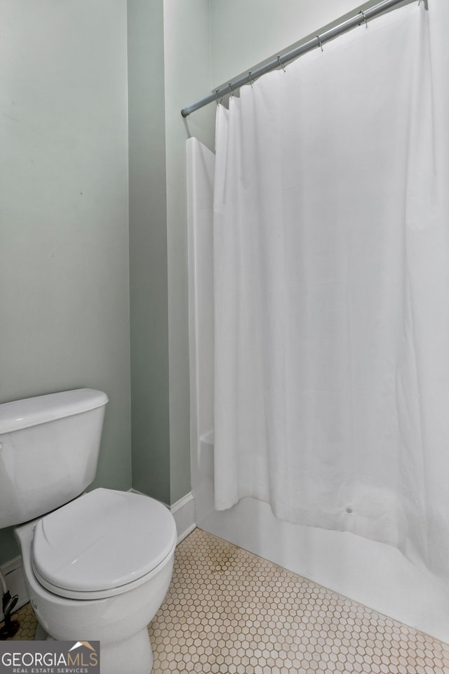 441 Crumbley Rd, Mcdonough, GA 30252 - bathroom featuring toilet, baseboards, and shower / bath combo with shower curtain
