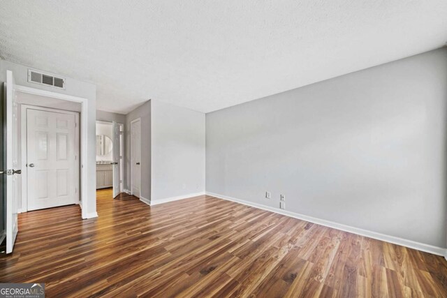 717 Beaufort Cir, Duluth, GA 30096 - unfurnished bedroom with baseboards, dark wood-style floors, and a textured ceiling