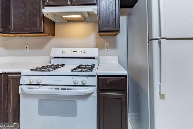 5614 Regency Forest Ct, Lithonia, GA 30038 - kitchen with white appliances, under cabinet range hood, and dark brown cabinets