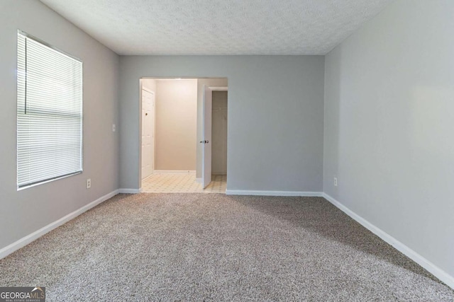 5614 Regency Forest Ct, Lithonia, GA 30038 - unfurnished bedroom featuring light colored carpet, a textured ceiling, baseboards, a walk in closet, and a closet