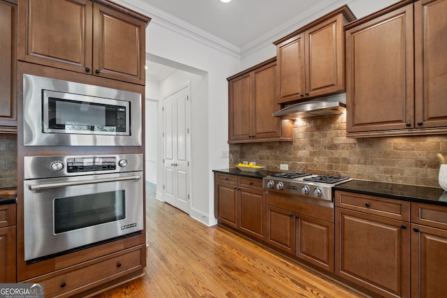 661 Lockton Pl # 9, Sandy Springs, GA 30342 - kitchen with appliances with stainless steel finishes, under cabinet range hood, light wood-style flooring, crown molding, and tasteful backsplash