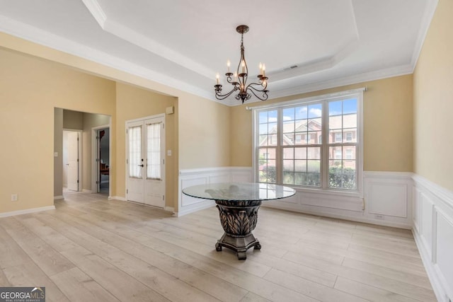 543 Serene Waters Trl, Jonesboro, GA 30236 - unfurnished dining area with a tray ceiling, a chandelier, a wainscoted wall, light wood finished floors, and french doors