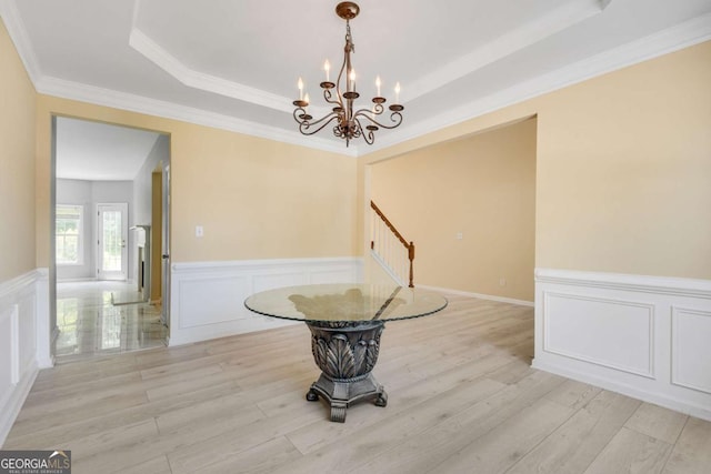 543 Serene Waters Trl, Jonesboro, GA 30236 - unfurnished dining area with a chandelier, a raised ceiling, a decorative wall, a wainscoted wall, and light wood-style floors