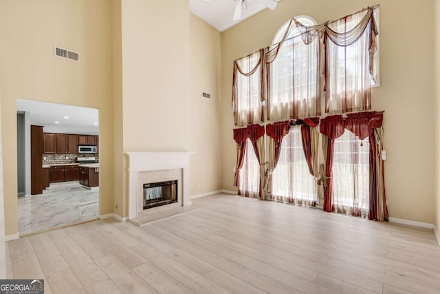 543 Serene Waters Trl, Jonesboro, GA 30236 - unfurnished living room featuring a towering ceiling, light wood-type flooring, healthy amount of natural light, and a premium fireplace